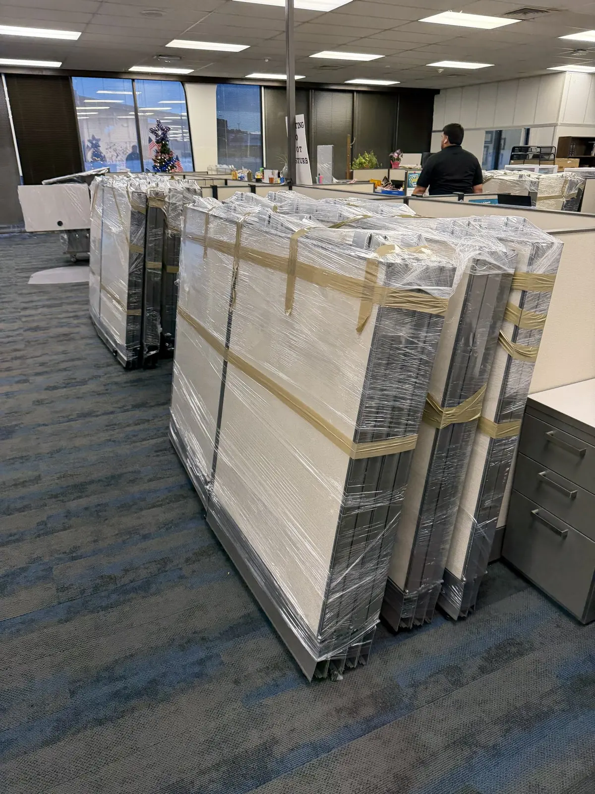 Workstation panels shrink-wrapped and staged inside an office