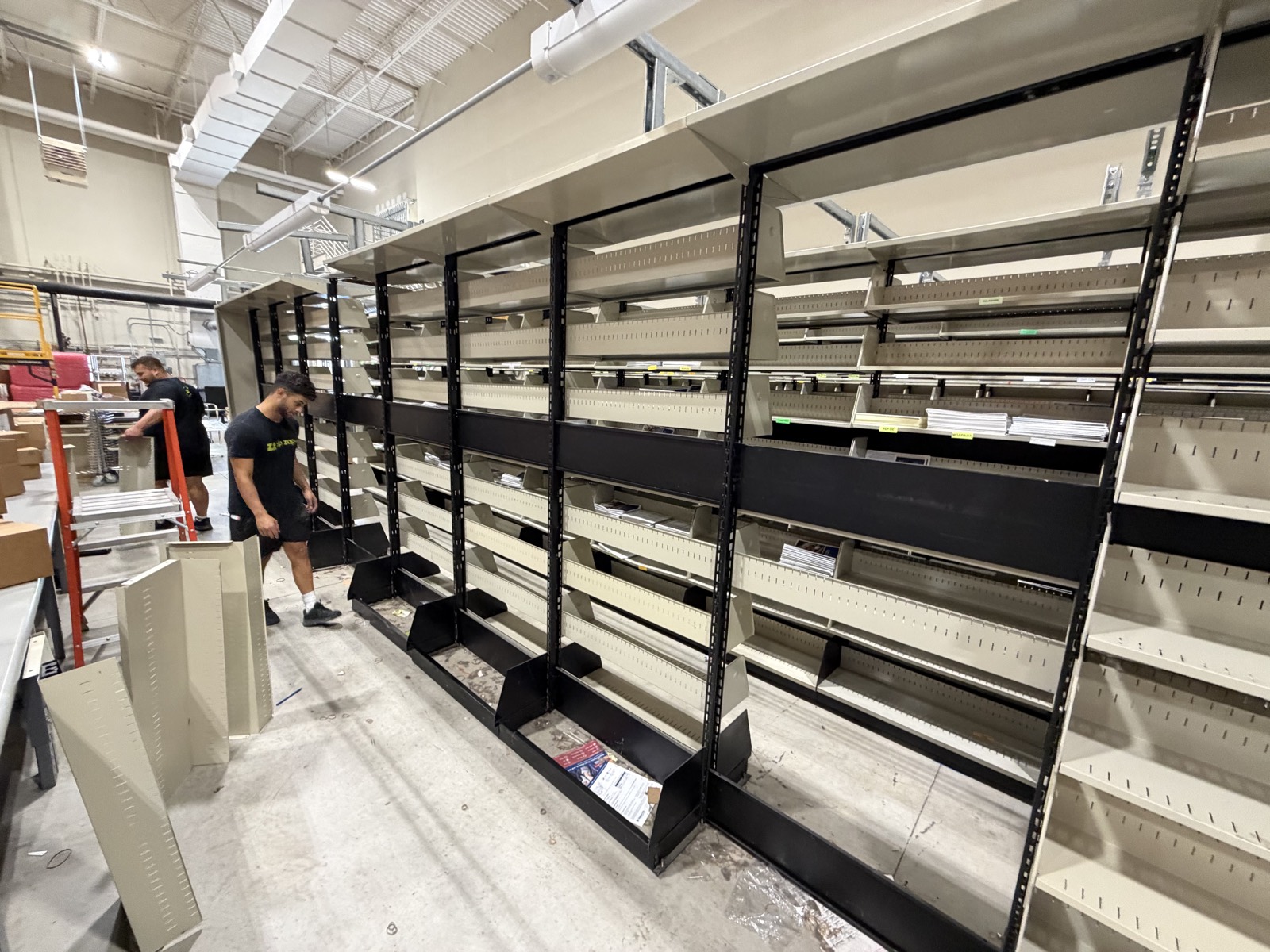 Zip Zap Moving crew in branded shirts installing commercial shelving during an office relocation in McKinney TX