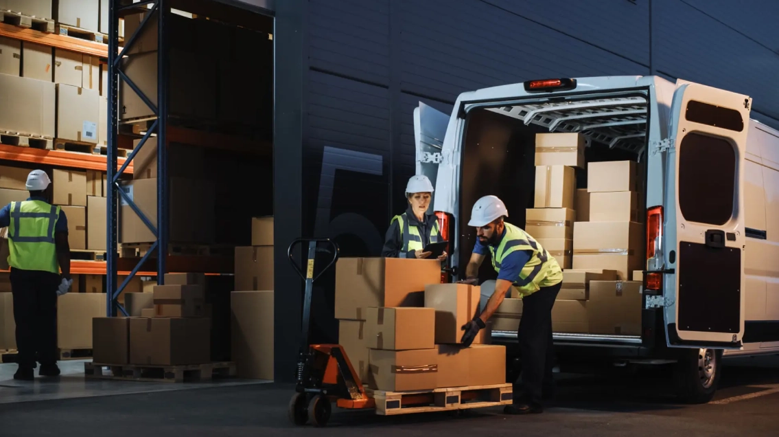 Movers carrying boxes from a warehouse into a van.